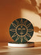 Dark green round ceramic coaster featuring a golden sun illustration with a serene, symmetrical face, delicate curved rays extending outward, and a small star detail on the forehead. The smooth, matte surface enhances the contrast between the deep green background and the warm golden design, giving it a celestial and vintage-inspired aesthetic.